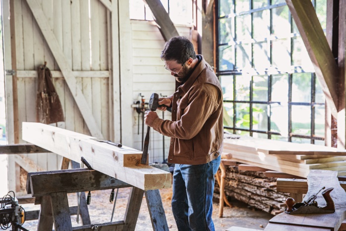 A person using a hammer to chisel a piece of wood

Description automatically generated